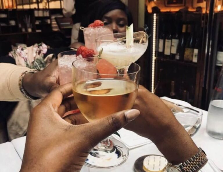 black women clinkling glasses in a toast at dinner