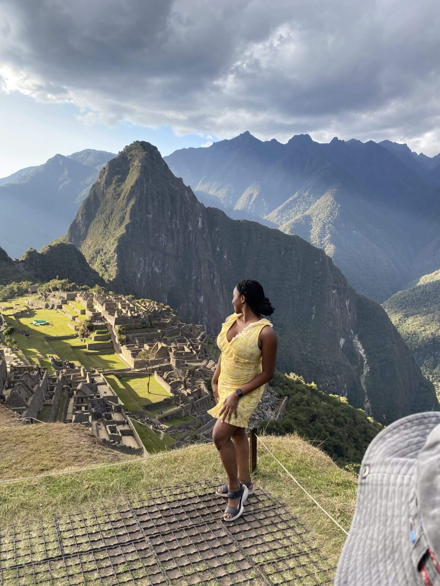 Girl in yellow dress looking out to Macchu Pichu Peru